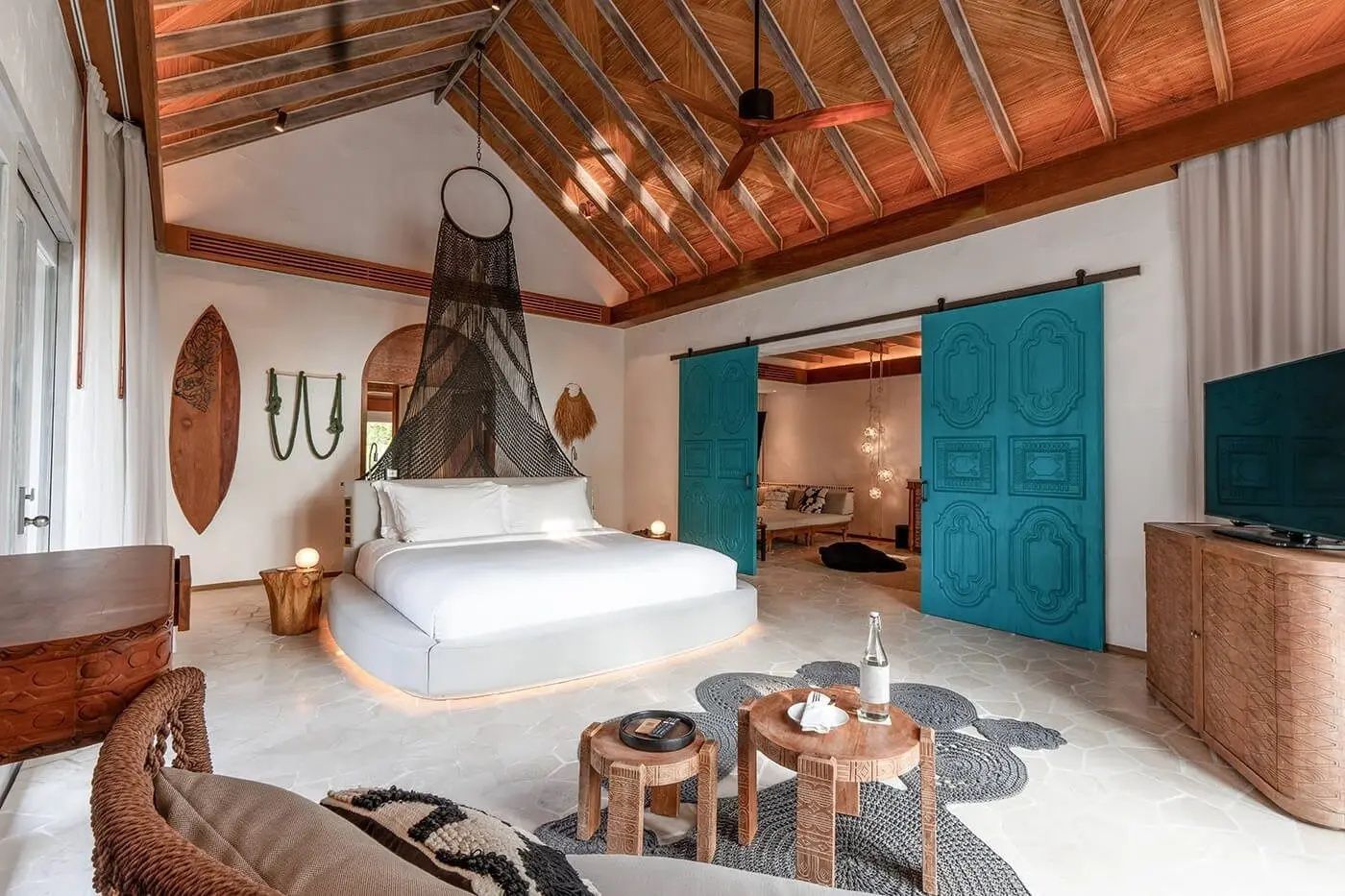 Geräumiges Schlafzimmer mit Holzdecke, rundem Bett und blauen Schiebetüren.