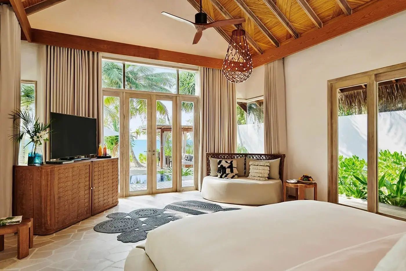 Helles Schlafzimmer mit Holzdecke, gemütlicher Sitznische und Blick auf den Strand und das Meer.
