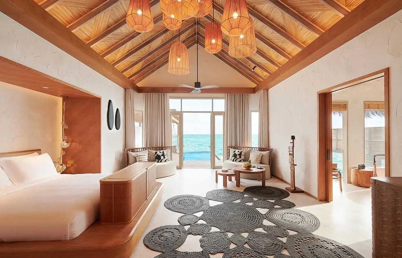 Geräumiges Villenzimmer mit Holzdecke, runden Teppichen, Sitzbereich und Blick auf das Meer