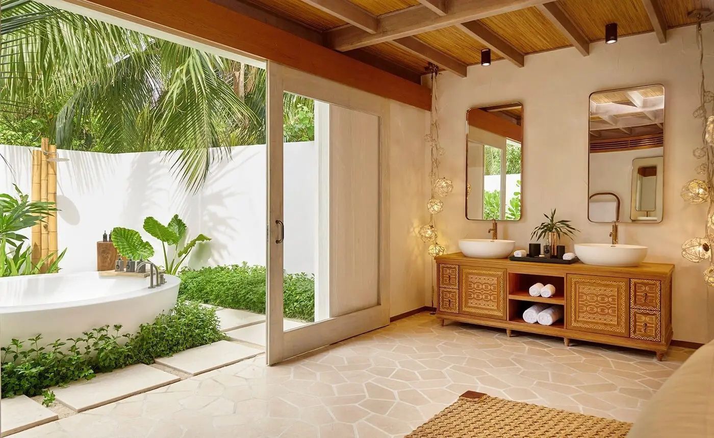 Badezimmer mit Holzwaschtisch, großem Spiegel und Übergang zum Außenbereich.