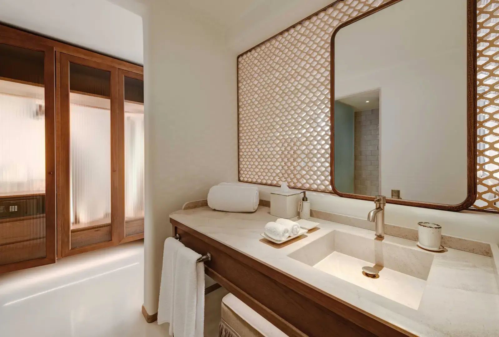 Badezimmer mit Holzwaschtisch, hellem Waschbecken, großem Spiegel und geflochtener Wanddekoration.