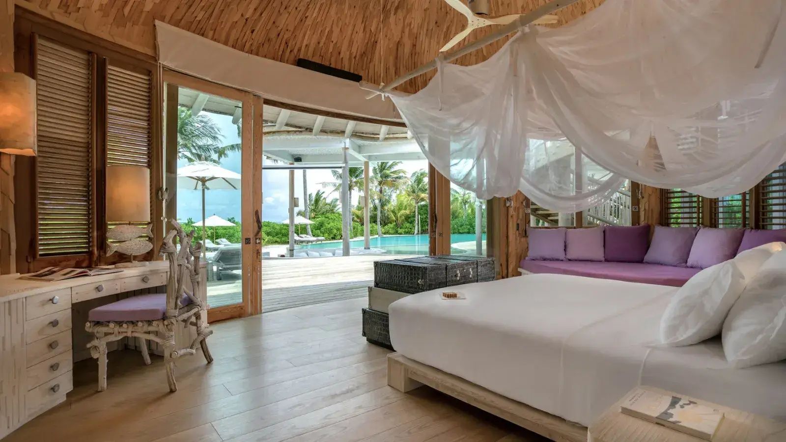 Schlafzimmer mit Doppelbett und geöffneten Glastüren zur Terrasse mit Pool und Meerblick.