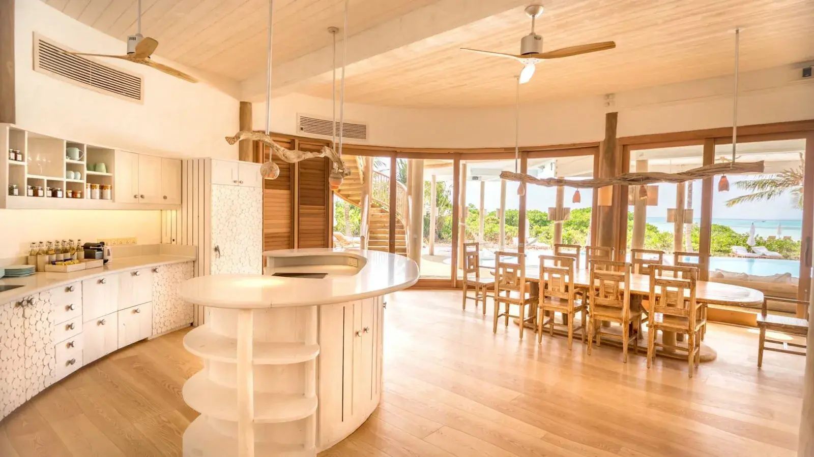 Heller Wohnbereich mit Kücheninsel aus Holz, Esstisch und großen Glasfronten ins Freie.