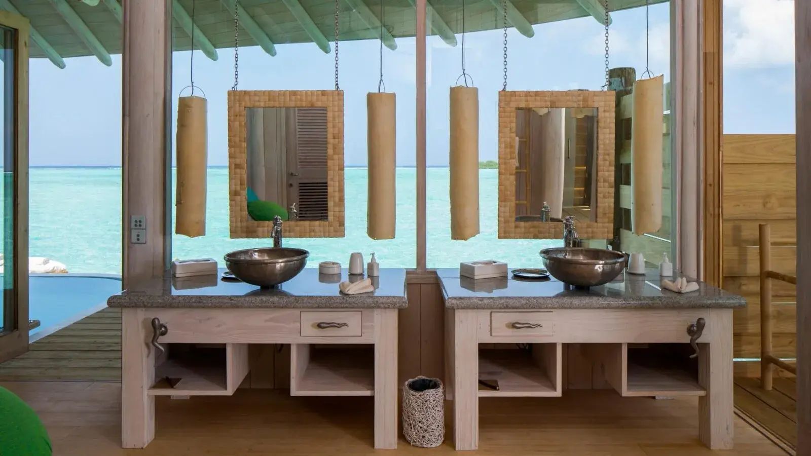 Doppelwaschtisch im Badezimmer mit zwei Holzspiegeln und Blick auf das blaue Meer.
