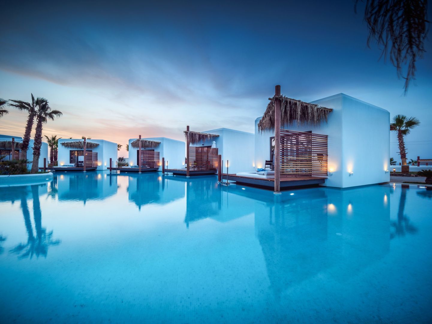 Moderne Bungalows an einer Swimmingpool-Lagune während der Abenddämmerung.
