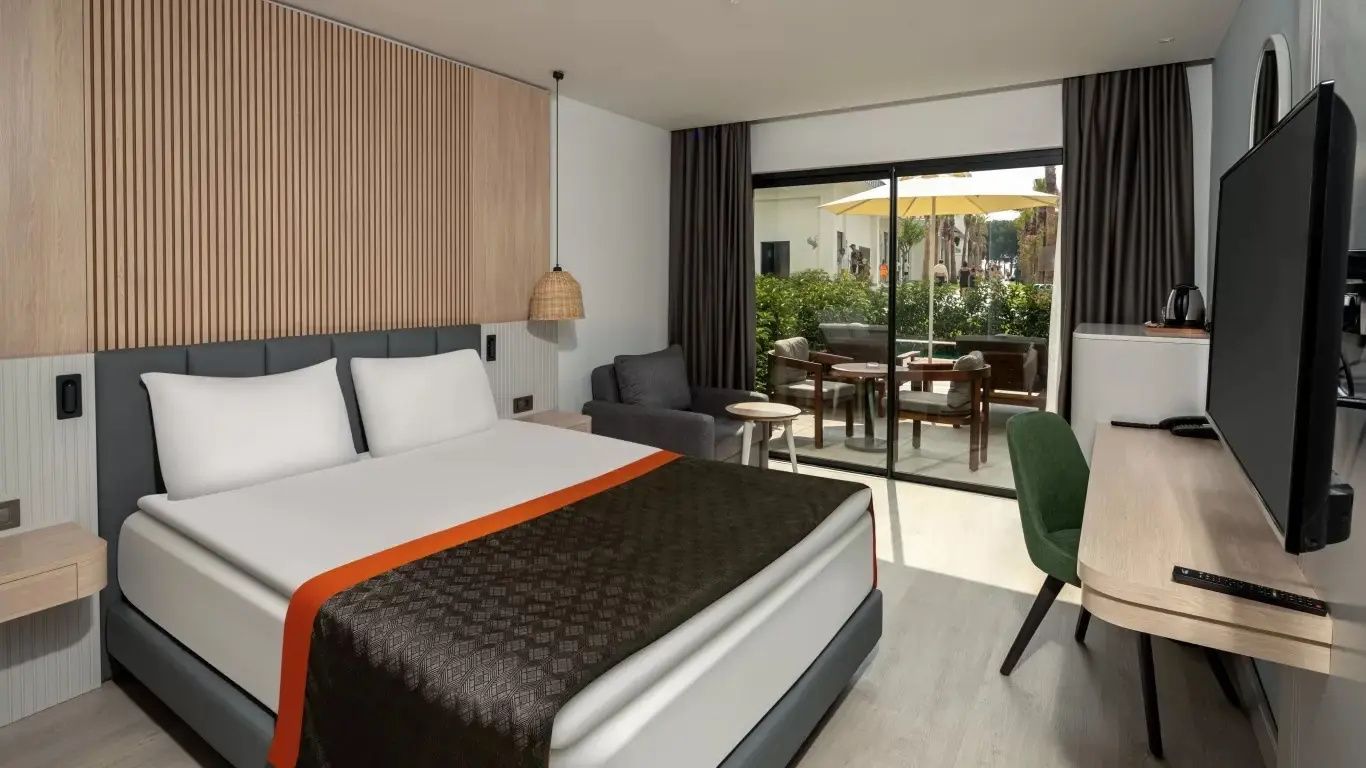 Modern eingerichtetes Hotelzimmer mit Doppelbett und Blick auf die eigene Terrasse.