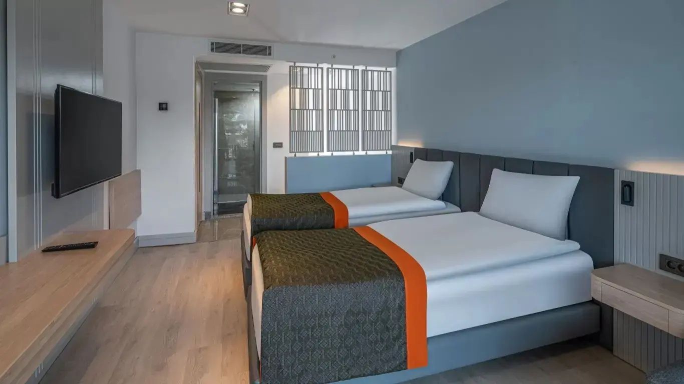 Zwei Einzelbetten in einem hellen Hotelzimmer mit blauer Wandgestaltung.
