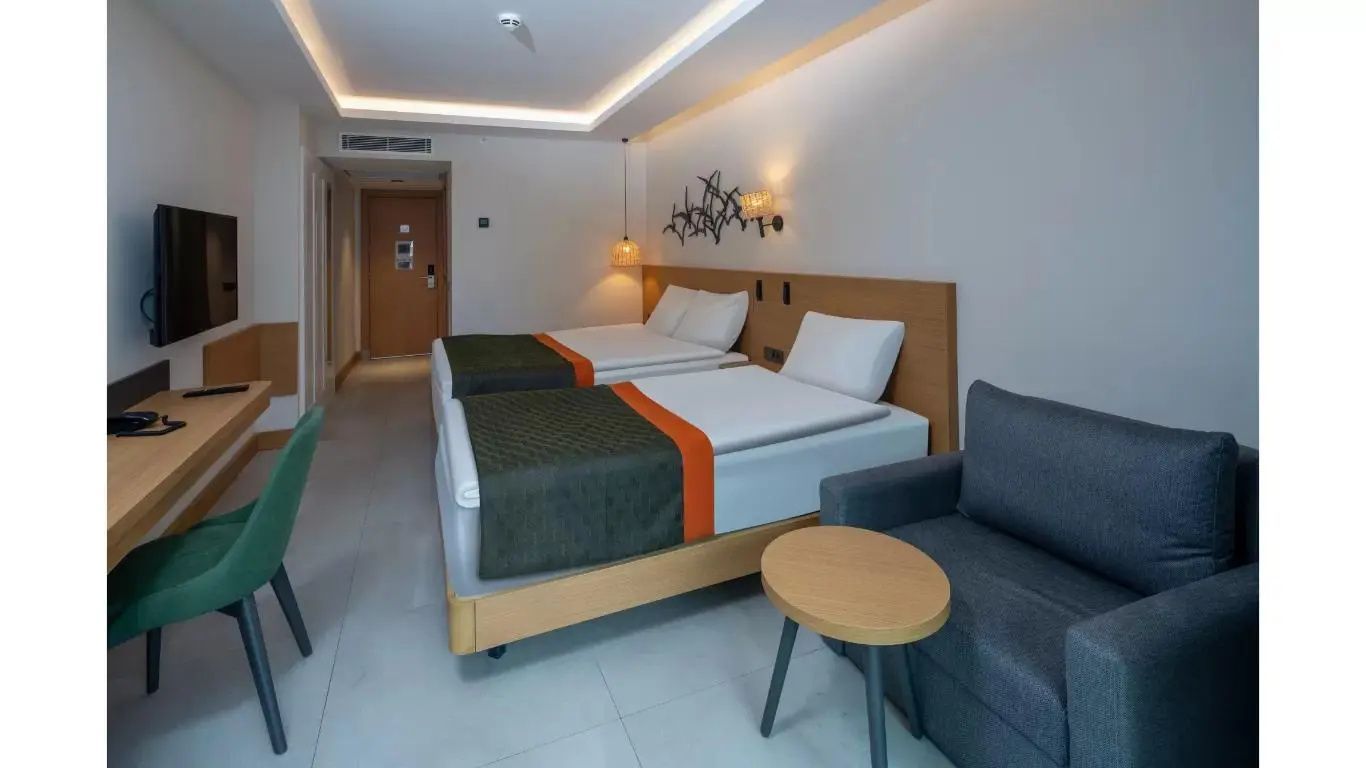 Ansicht eines Hotelzimmers mit Betten, Polstersessel und Eingangsbereich