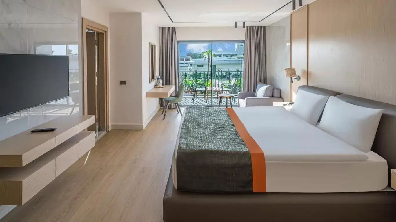 Hotelzimmer mit Doppelbett, Sitzecke und Balkon mit Blick auf den Garten.