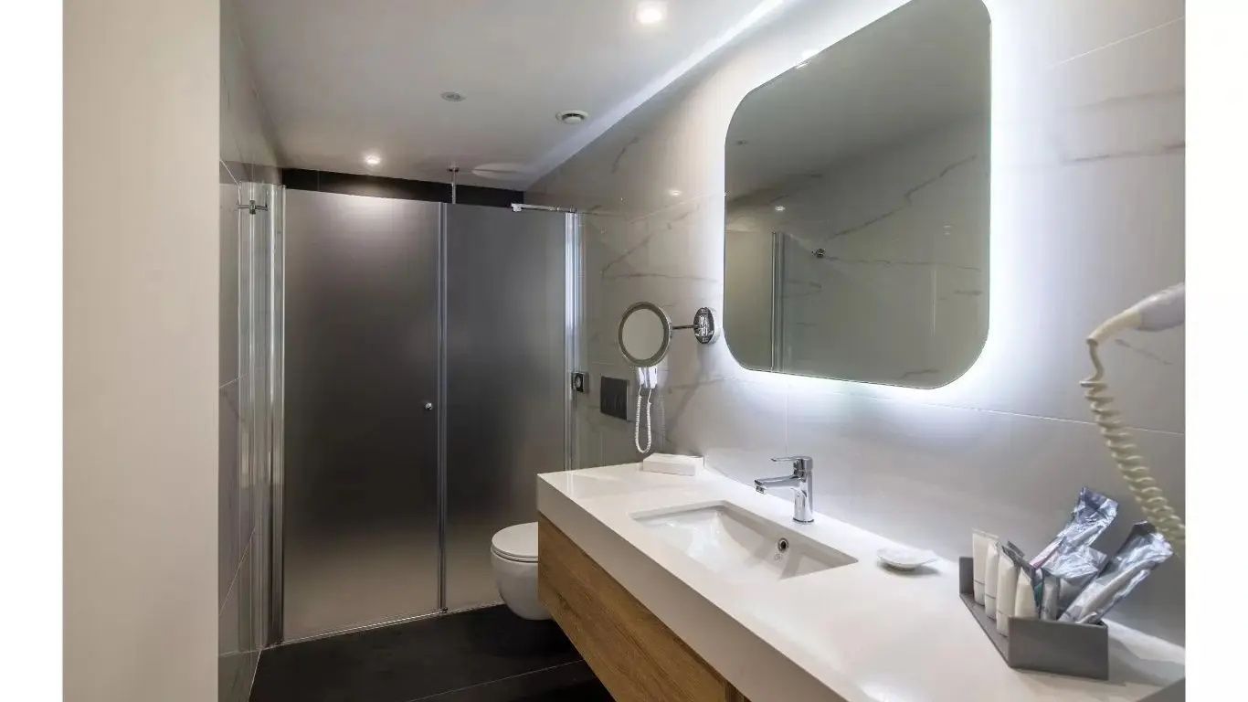 Modernes Badezimmer mit beleuchtetem Spiegel, Waschtisch und Dusche.