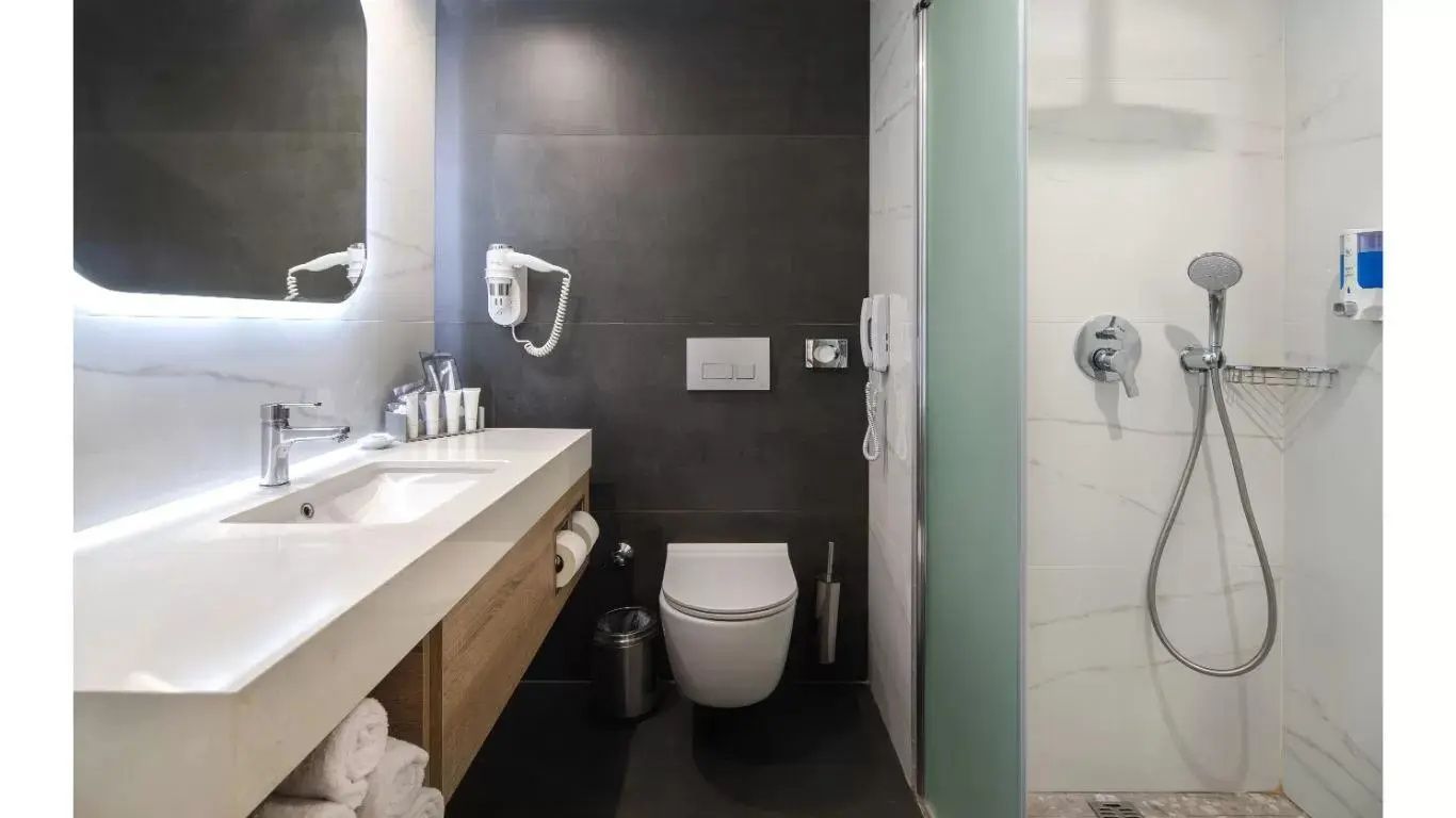 Badezimmer mit dunkler Akzentwand, Waschbecken, Wand-WC und Dusche