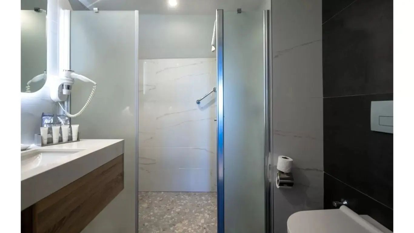 Badezimmerbereich mit einer modernen Dusche hinter Glastüren und hellem Fliesendesign.
