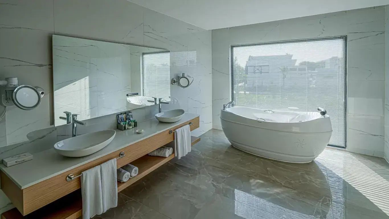 Geräumiges Badezimmer mit Doppelwaschbecken, großem Spiegel und Badewanne.