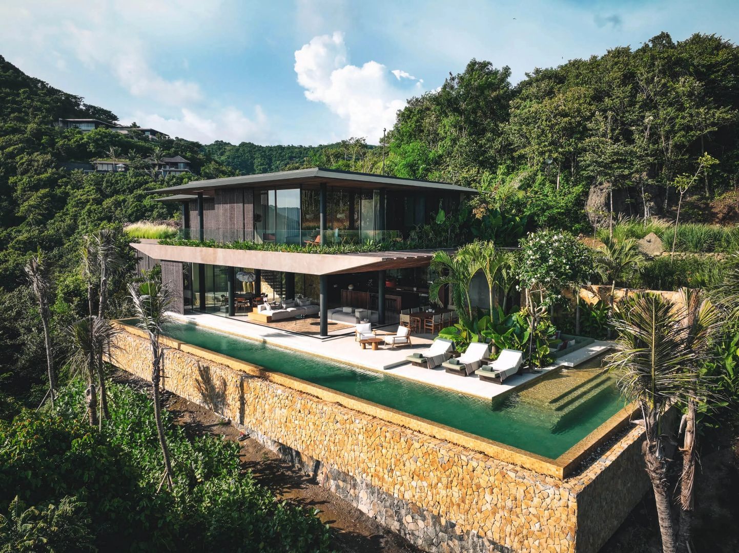 Moderne zweistöckige Villa mit langem Swimmingpool und Liegestühlen im Garten