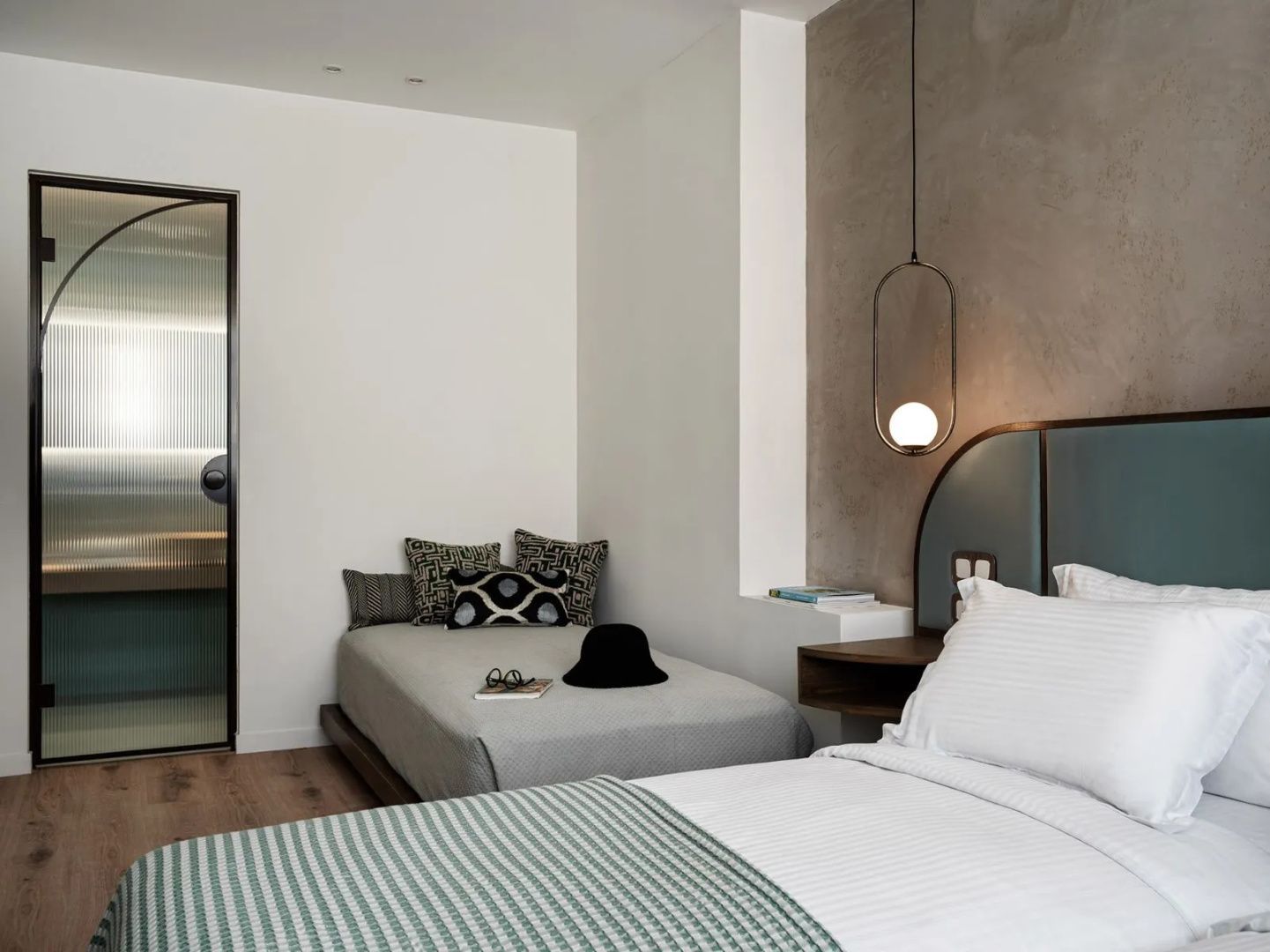Ecke eines Hotelzimmers mit kleinem Schlafsofa, Kissen und Nachttischlampe.