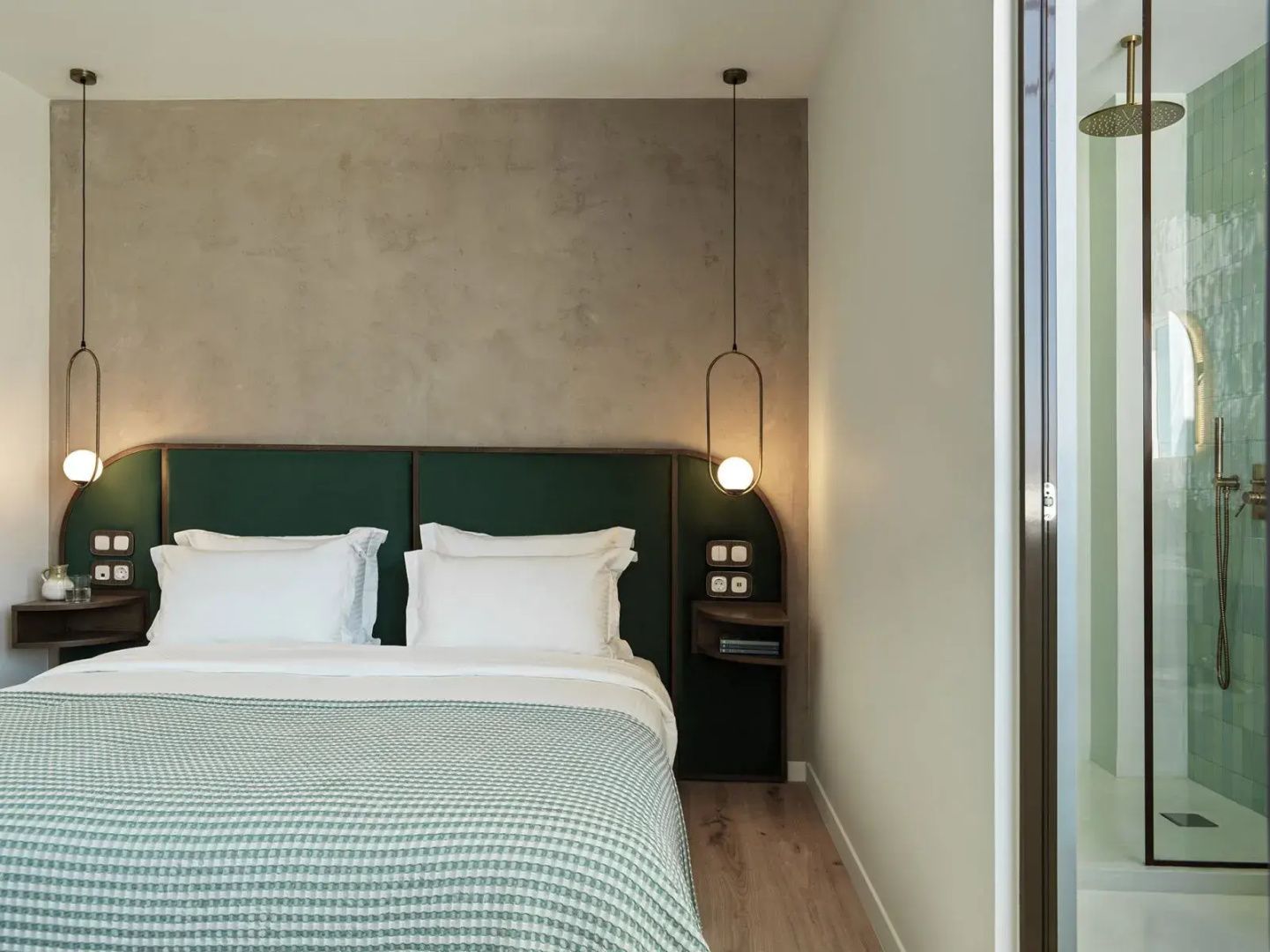 Doppelbett mit grünem Kopfteil, weißer Bettwäsche und moderner Hängeleuchte.