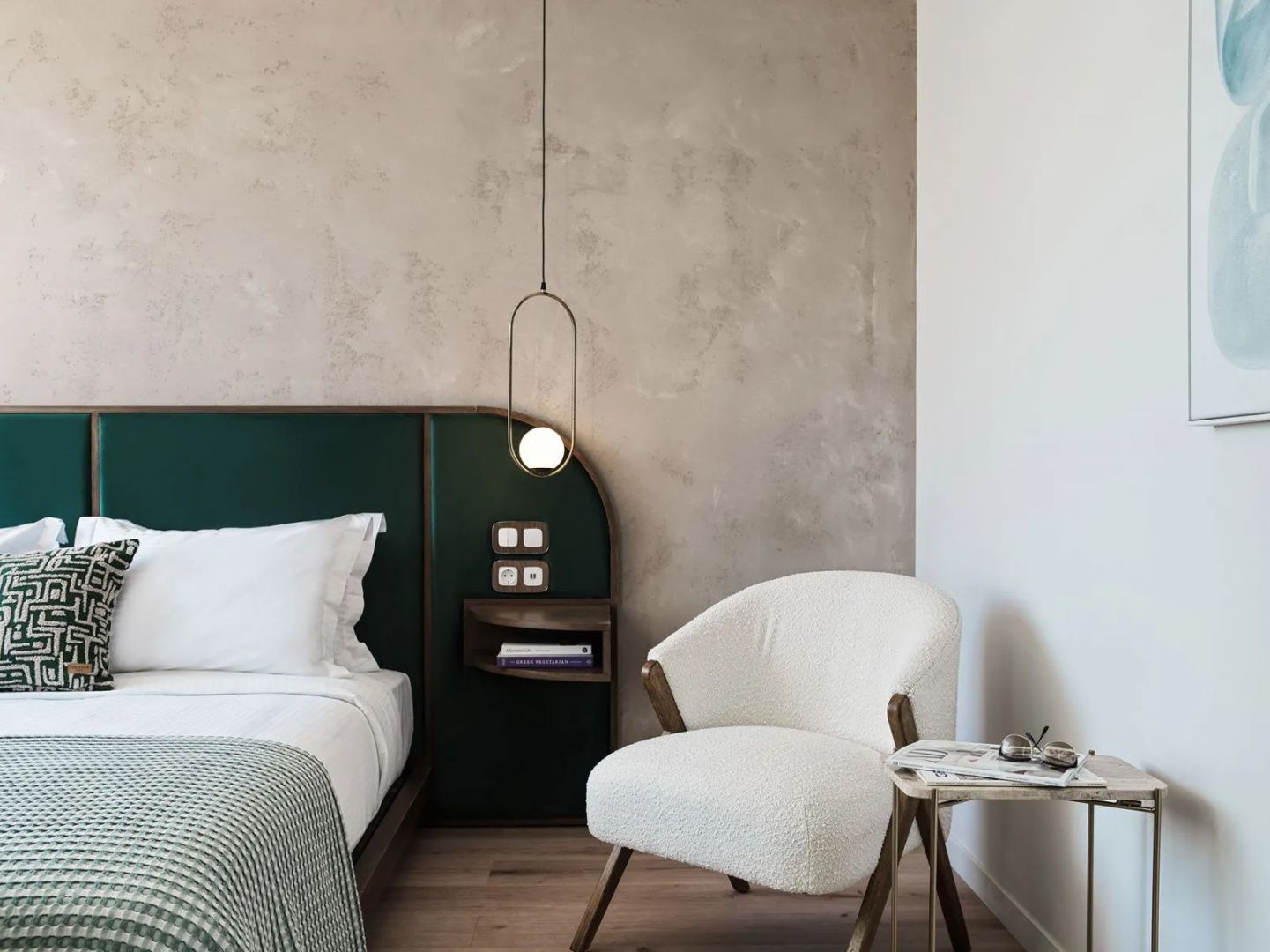 Sitzbereich im Hotelzimmer mit weißem Sessel, Beistelltisch und Hängeleuchte.