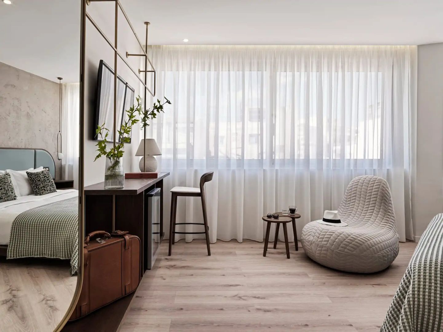 Wohnbereich im Zimmer mit Sessel, kleinen Holztischen und Kofferablage.