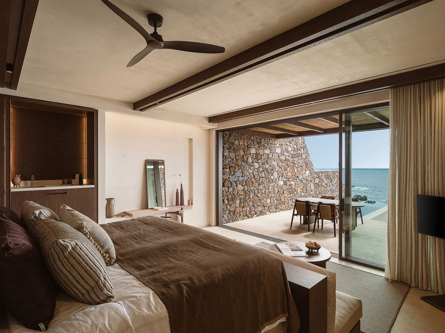 Modernes Schlafzimmer mit Doppelbett und Zugang zur Terrasse mit Meerblick.