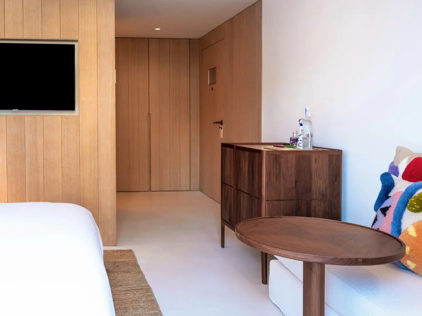 Einrichtung eines Hotelzimmers mit Holzverkleidung, Schrank und kleinem Beistelltisch.