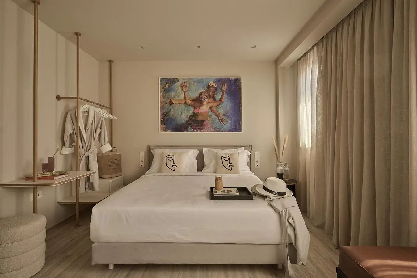 Helles Zimmer mit Doppelbett, buntem Bild an der Wand und bodentiefen Vorhängen.