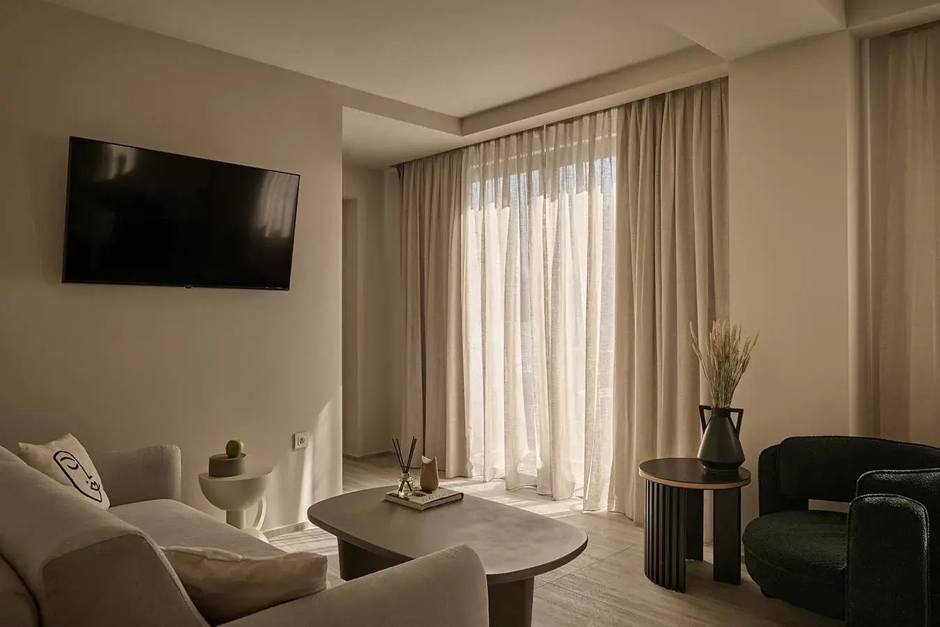 Wohnbereich im Zimmer mit Sofa, leichtem Couchtisch und hellen Vorhängen
