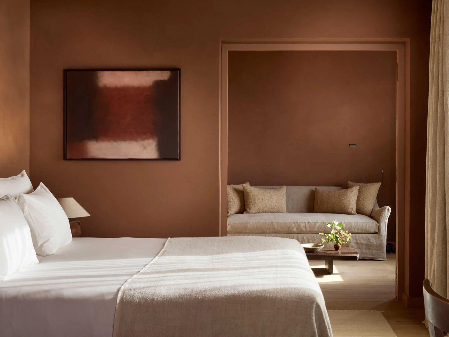 Hotelzimmer mit braunen Wänden, Bett und integrierter Sitzecke mit Sofa.