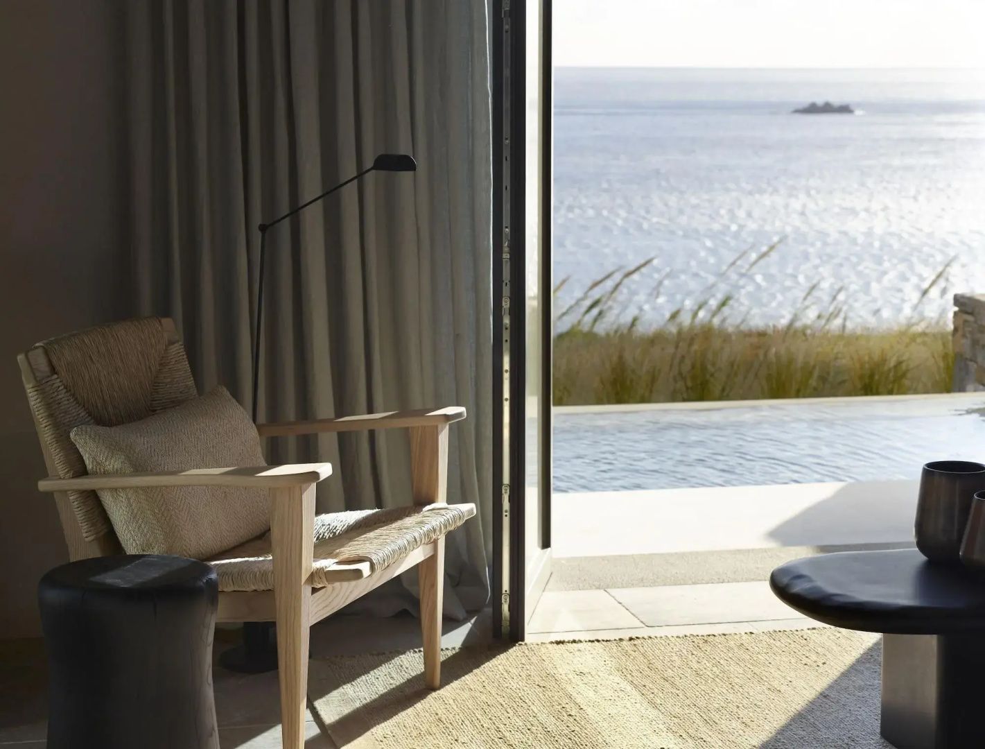 Sitzecke einer Suite im Kalesma Mykonos mit offener Tür zur Terrasse und Blick auf die Ägäis