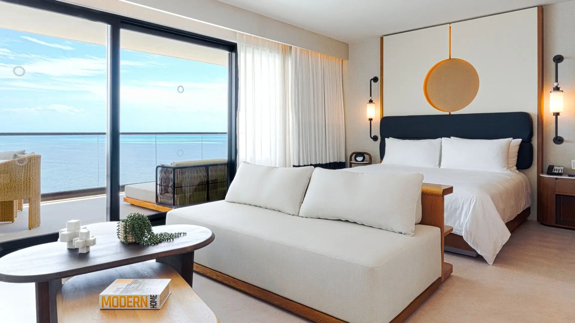 Helles Hotelzimmer mit gemütlichem Sofa, Doppelbett und Balkon mit Blick auf das türkisblaue Meer.
