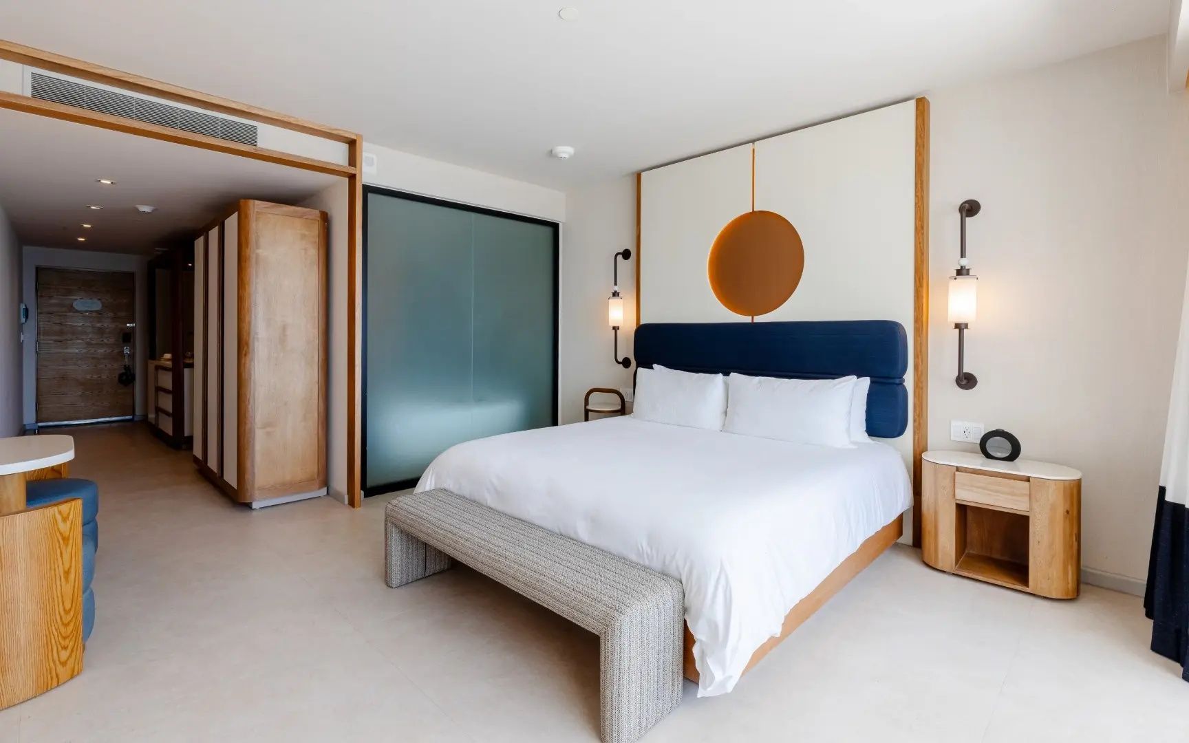 Modern eingerichtetes Hotelzimmer mit Doppelbett, weißer Bettwäsche und Holzschrank.