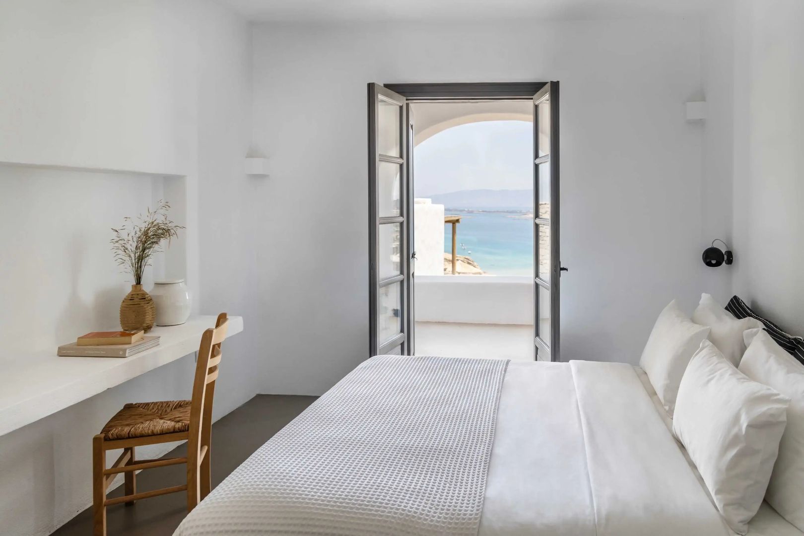 Blick aus dem Schlafzimmer durch eine geöffnete Tür auf das blaue Meer.