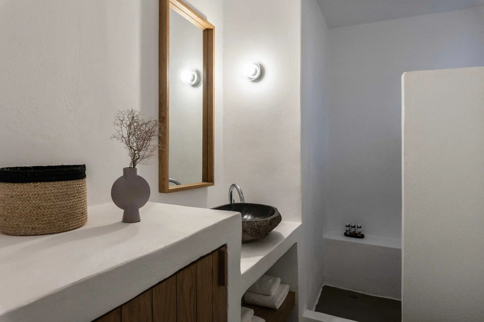 Weißes Badezimmer mit Steinwaschbecken auf einem gemauerten Waschtisch und Wandspiegel.