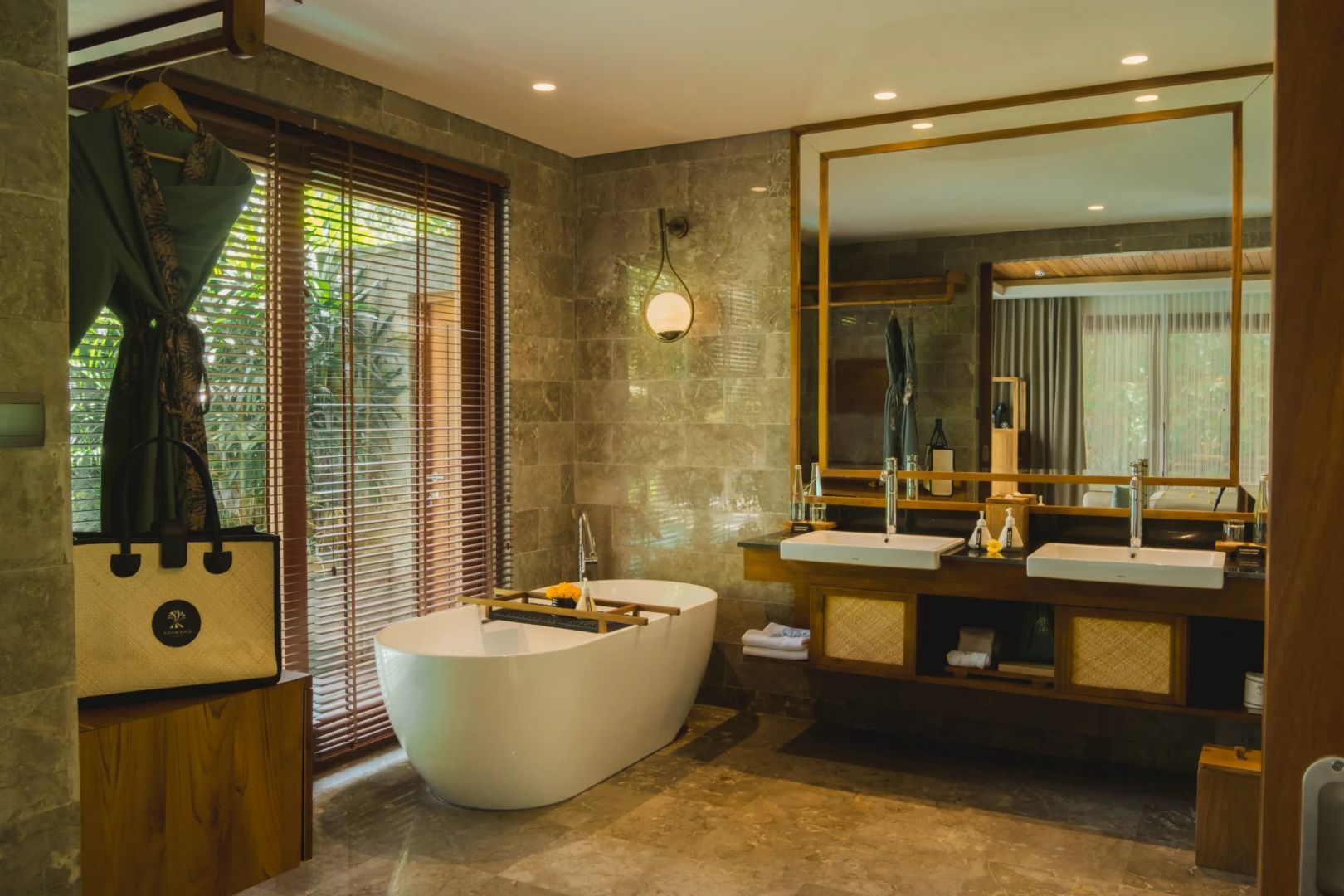 Badezimmer mit freistehender Badewanne, Doppelwaschtisch und großem Spiegel.