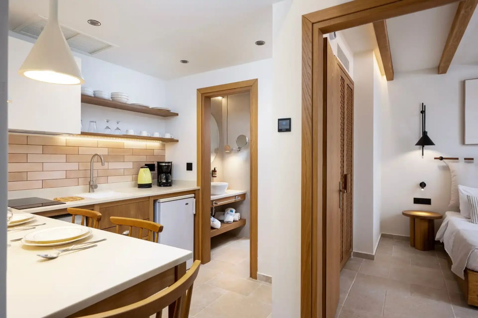 Heller Wohnbereich mit Kitchenette, Esstisch und Durchgang zum Badezimmer.