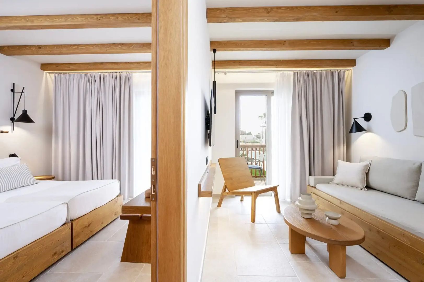 Blick auf Schlafbereich und Wohnbereich einer Suite mit Deckenbalken aus Holz.