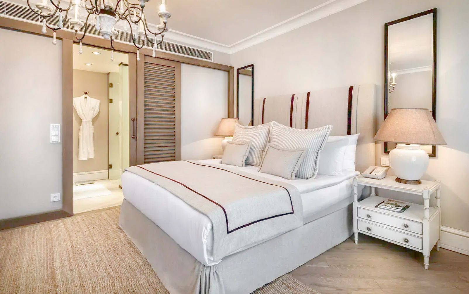 Großes Doppelbett in hellem Schlafzimmer mit Schiebetür zum angrenzenden Badezimmer.