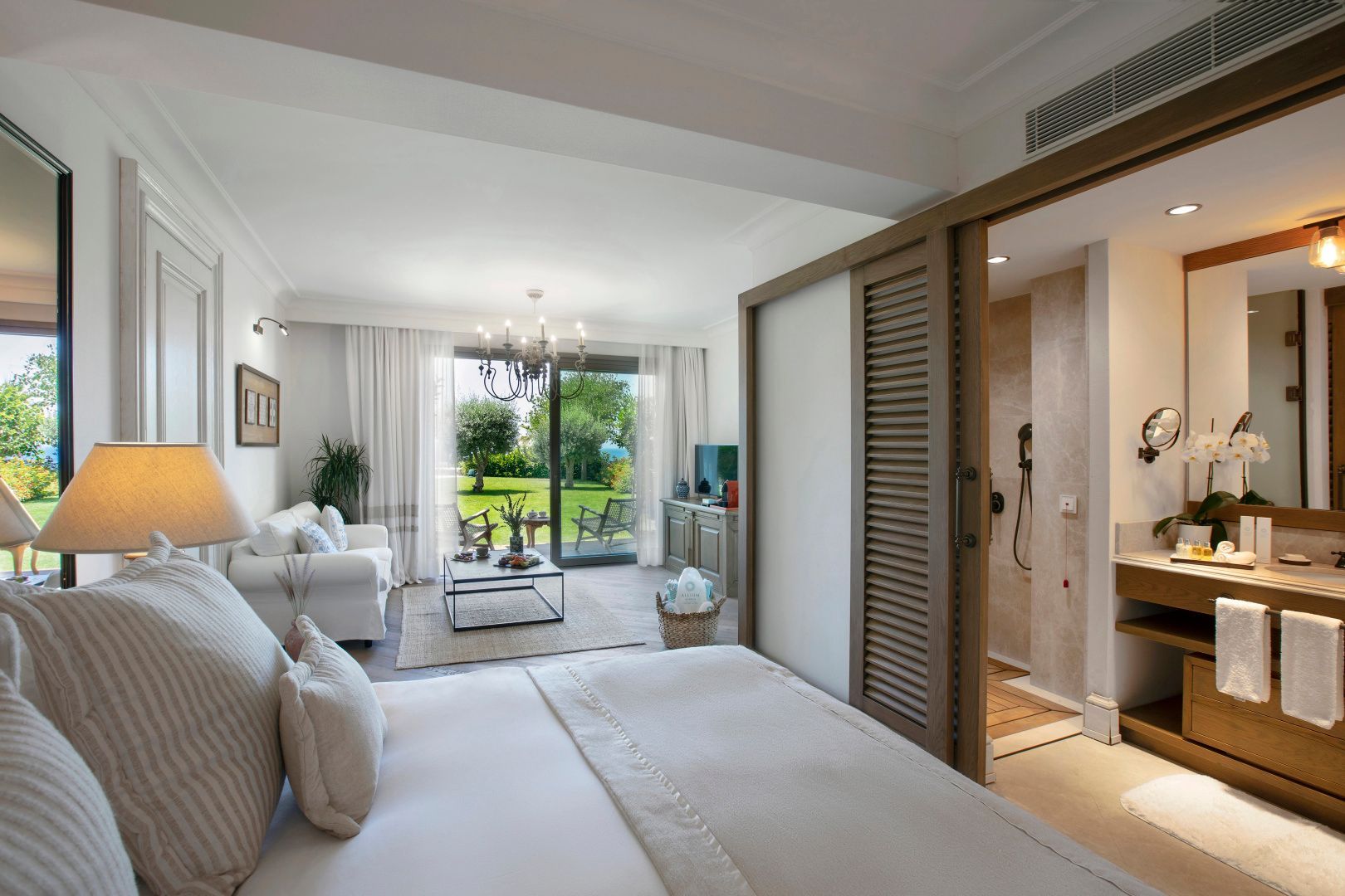 Schlafzimmer mit Blick auf die Terrasse, ein Sofa im Wohnbereich und das Badezimmer.