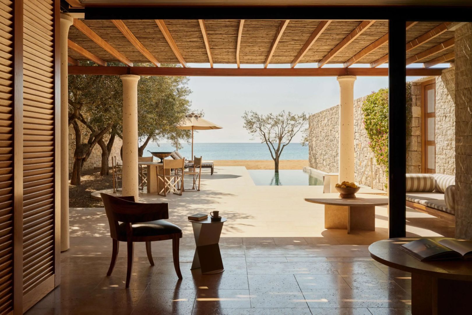 Überdachter Sitzbereich mit Holzdecke und Säulen mit Blick auf Terrasse, Pool und Meer.