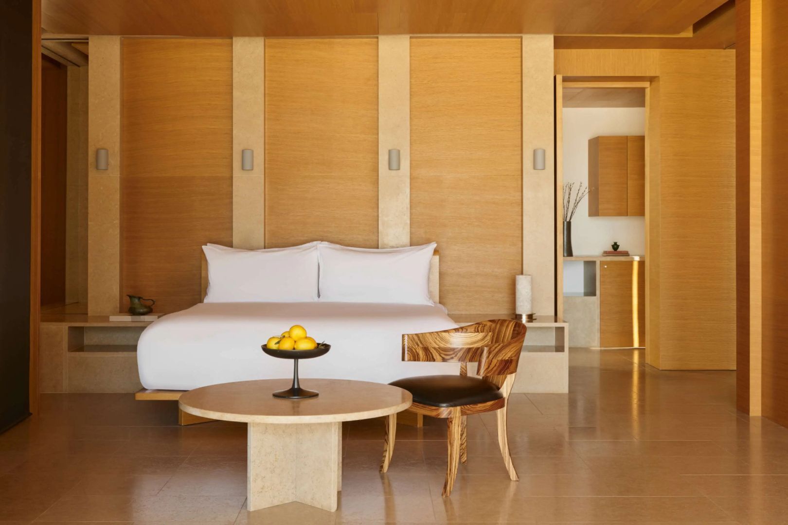 Schlafzimmer mit Doppelbett, Holzverkleidung, modernem Stuhl und kleinem Tisch.