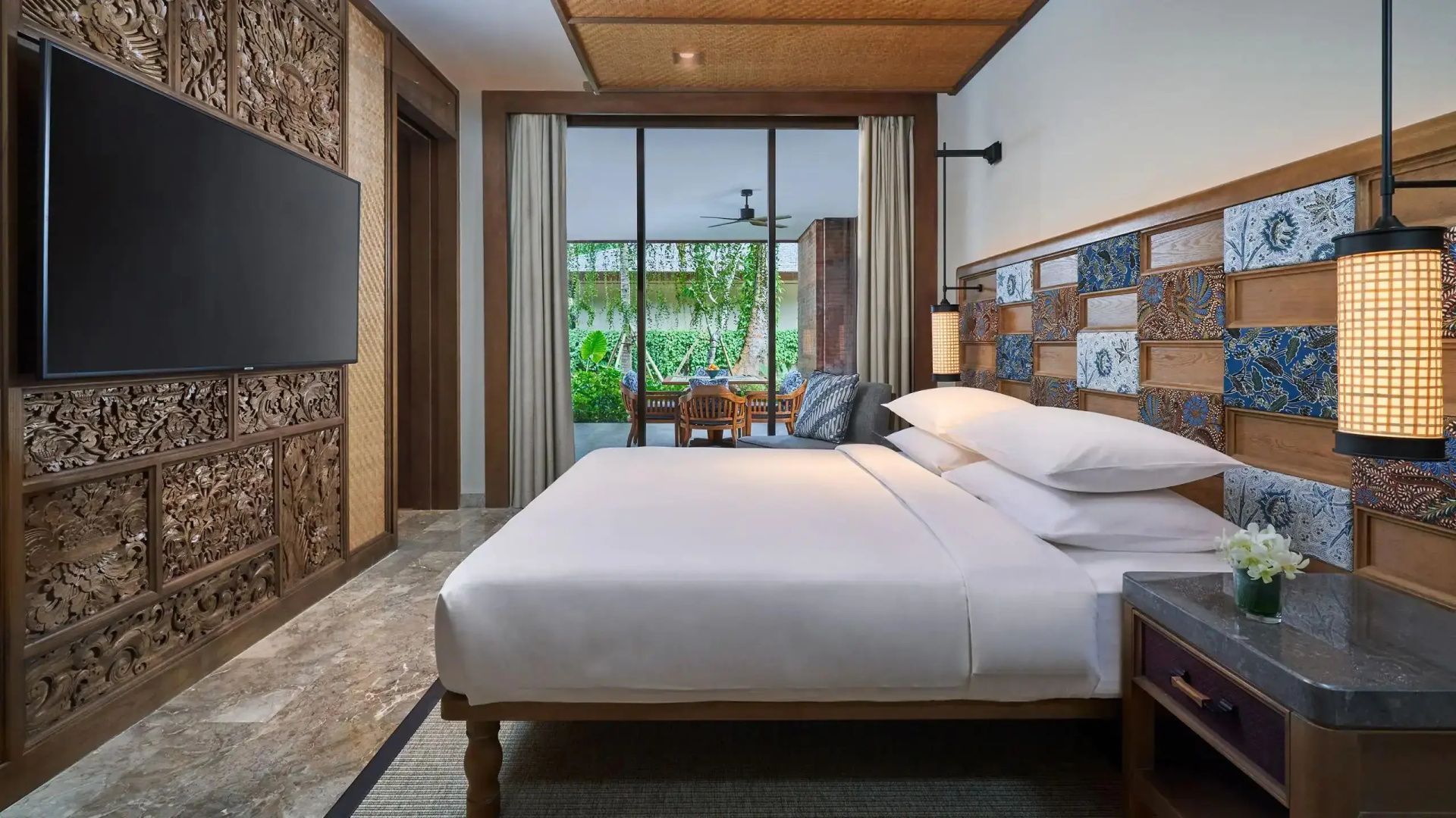 Doppelbett im Hotelzimmer mit Holzdekoration und Blick auf den Garten.