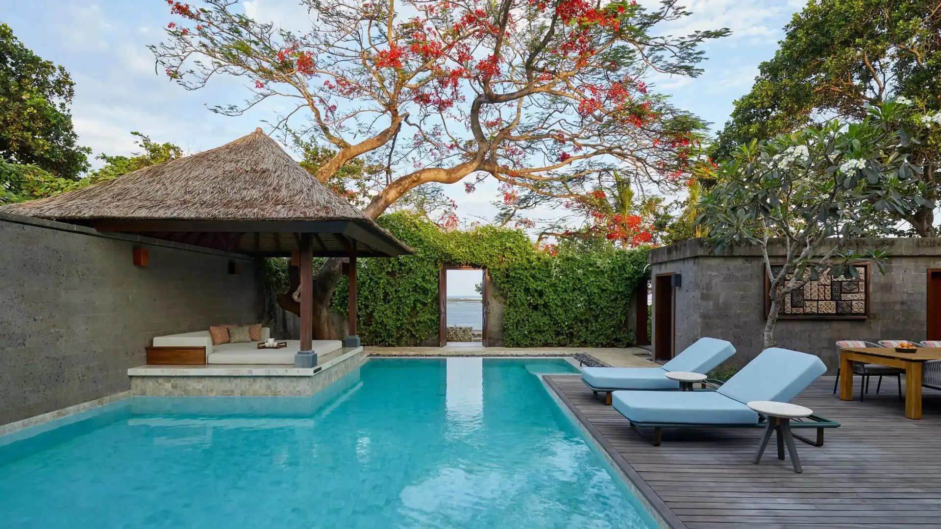 Privater Außenpool mit Liegen, Pavillon und blühendem Baum im Garten.