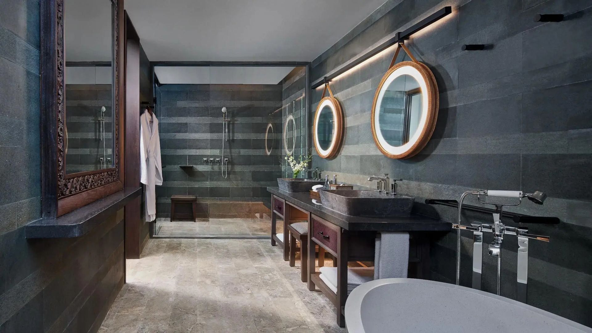 Badezimmer mit zwei Waschbecken, runden beleuchteten Spiegeln und Dusche hinter Glas.