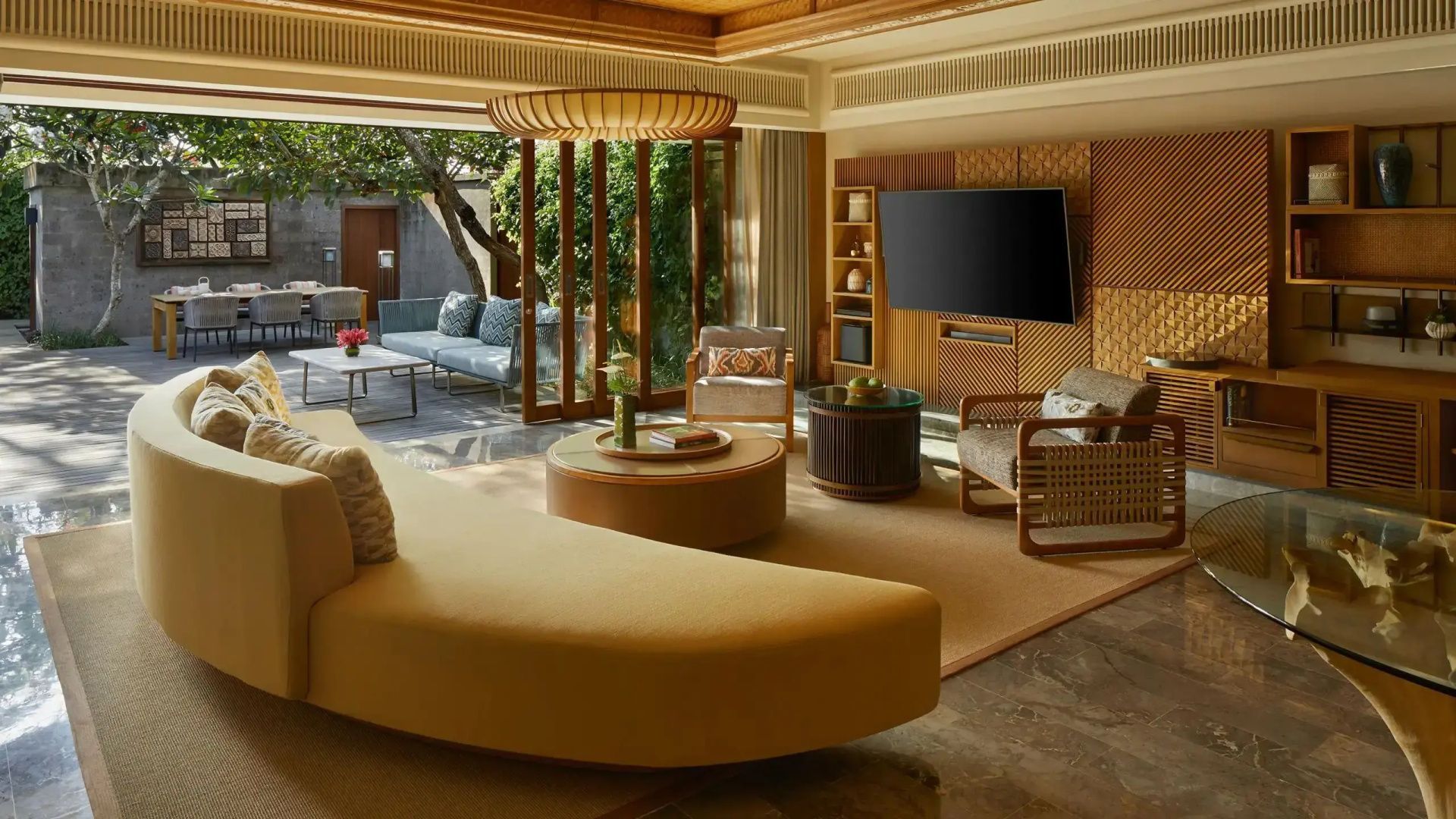 Geräumiger Wohnbereich mit gelbem Sofa, Fernseher und Übergang zur Terrasse.