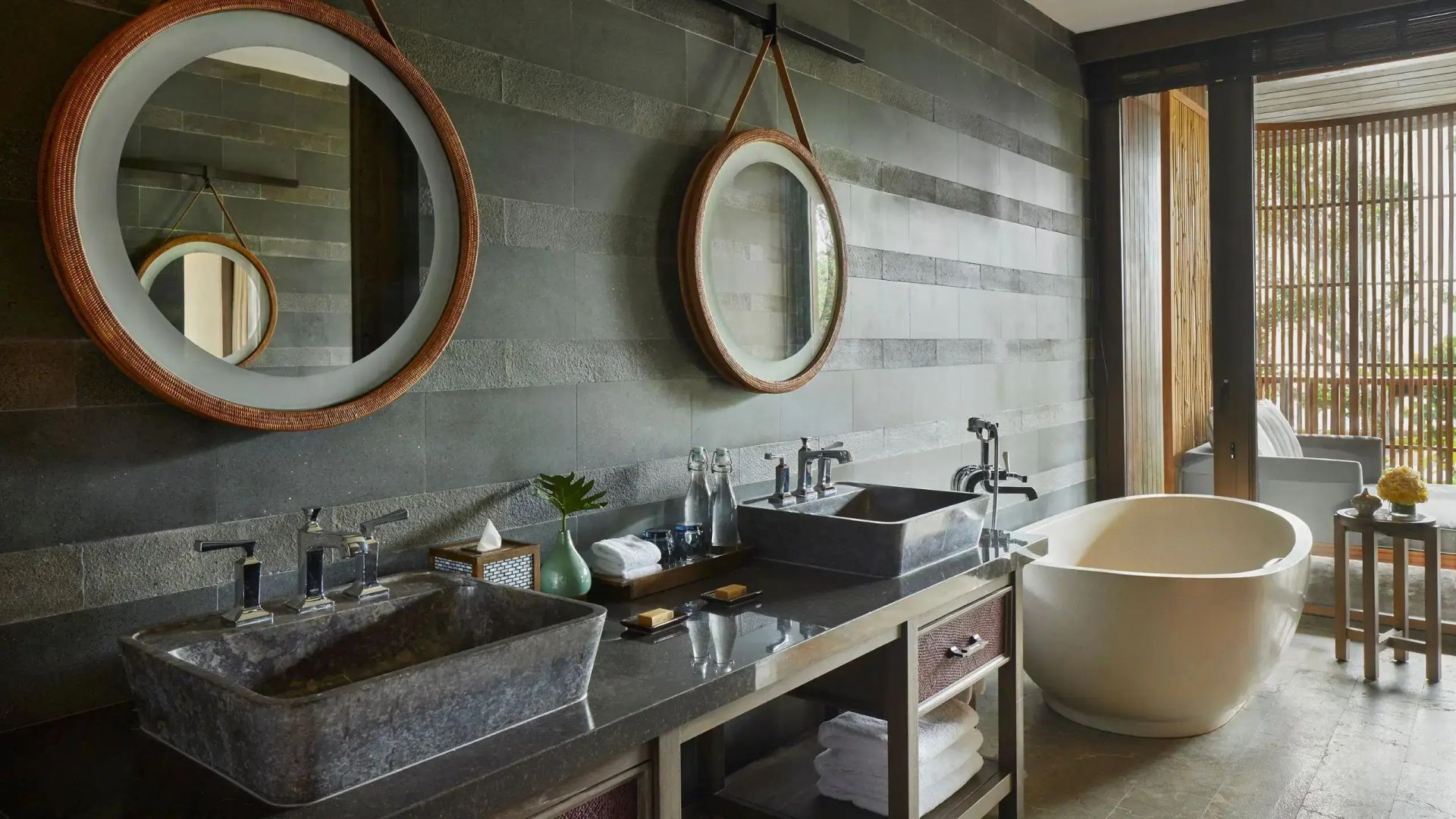Badezimmer mit doppelten Steinwaschbecken, runden Spiegeln und einer freistehenden Badewanne.