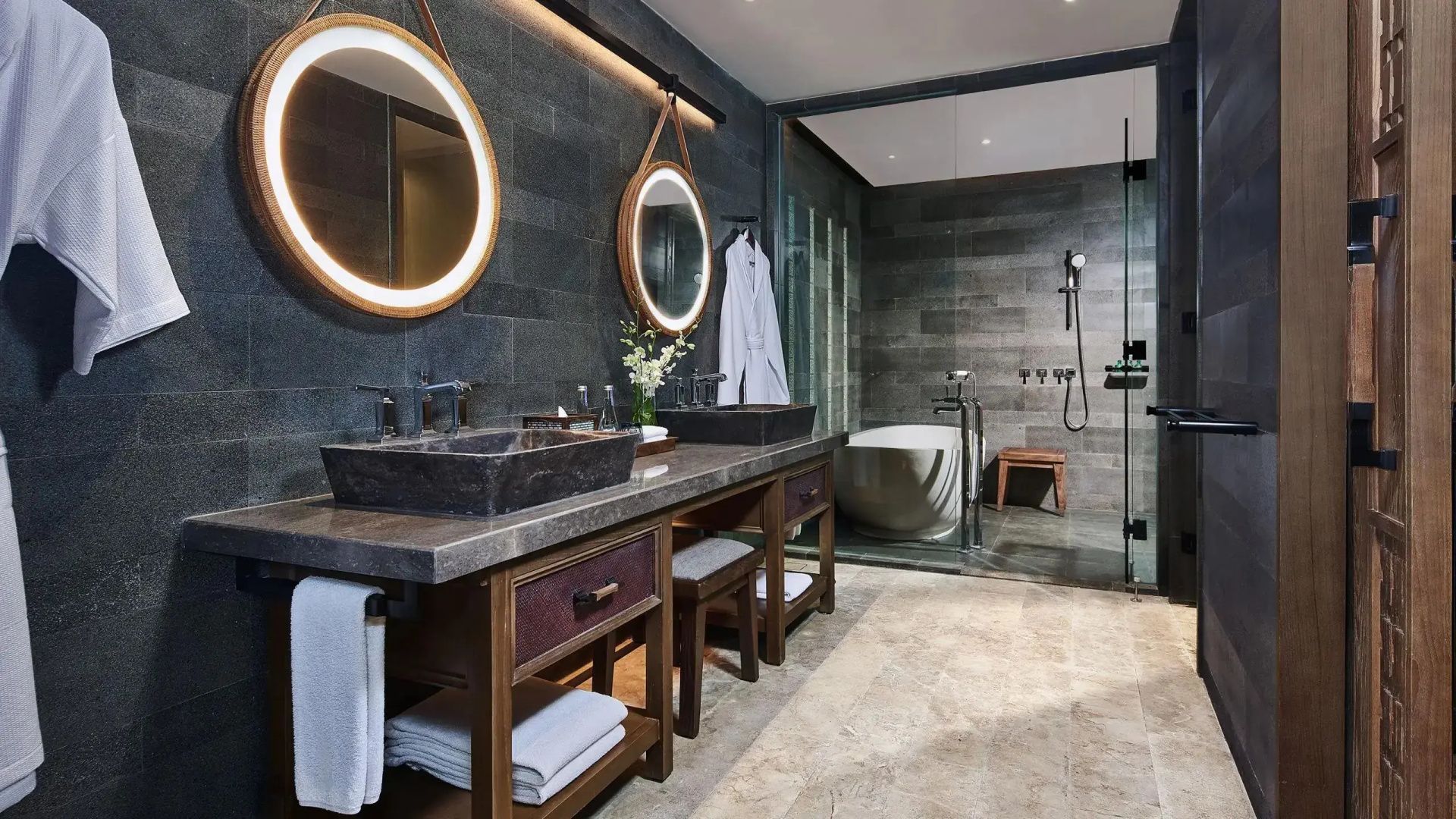 Badezimmer mit Doppelwaschtisch, beleuchteten Spiegeln und Badewanne