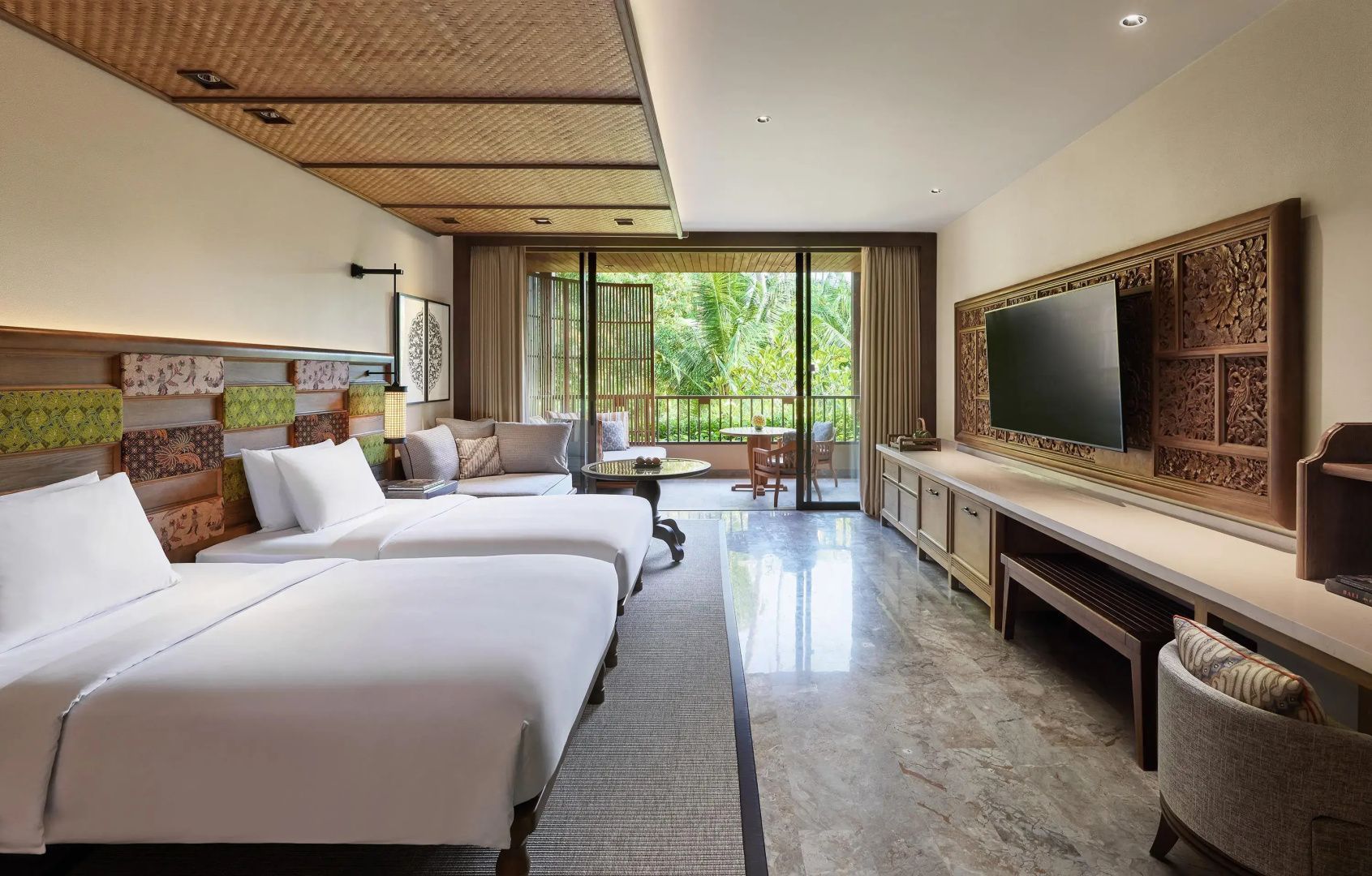 Geräumiges Hotelzimmer mit zwei Betten, Fernseher und Balkon im Grünen.