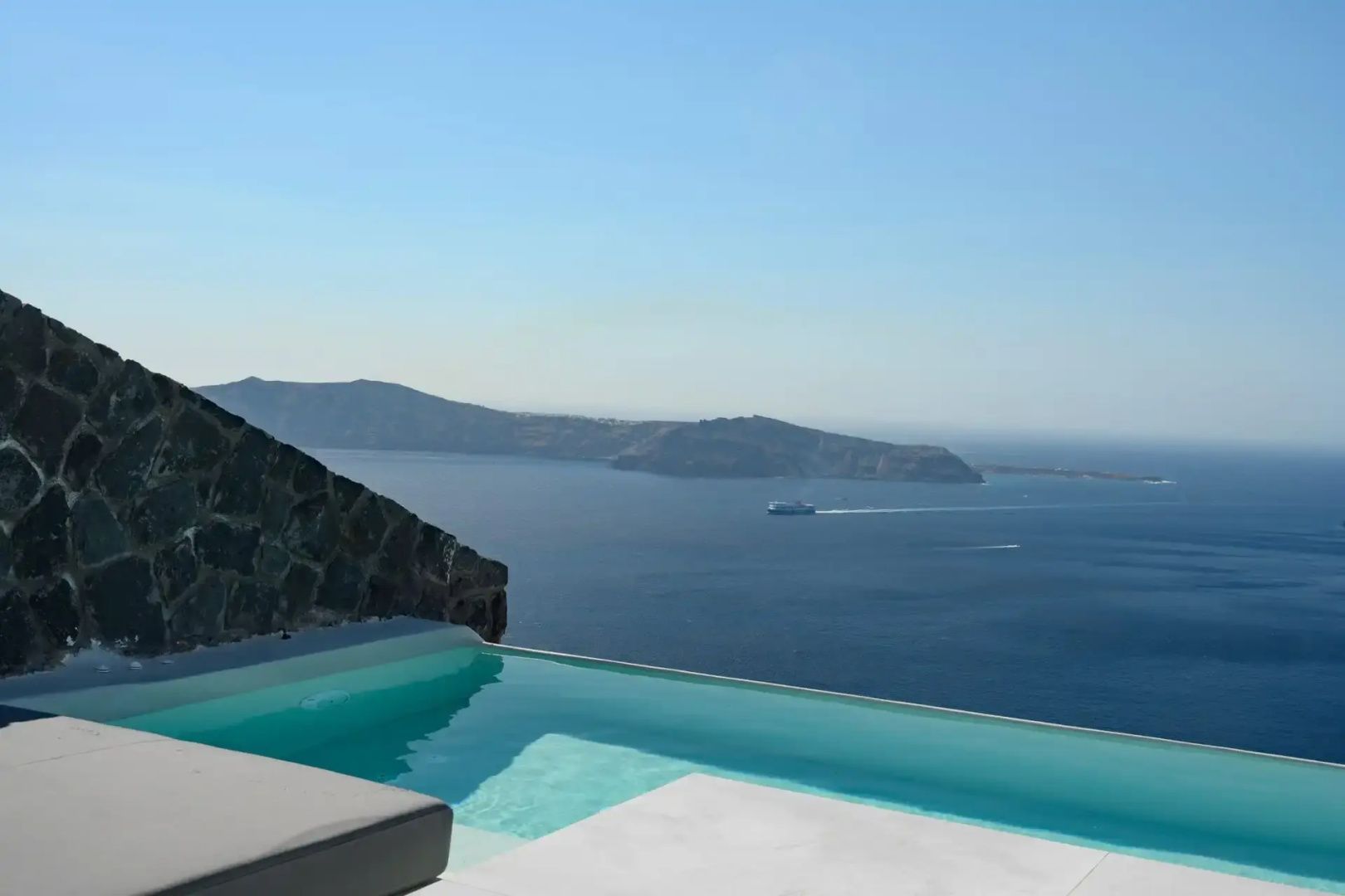 Infinitypool auf einer Terrasse mit freiem Blick auf das blaue Meer und entfernte Inseln.
