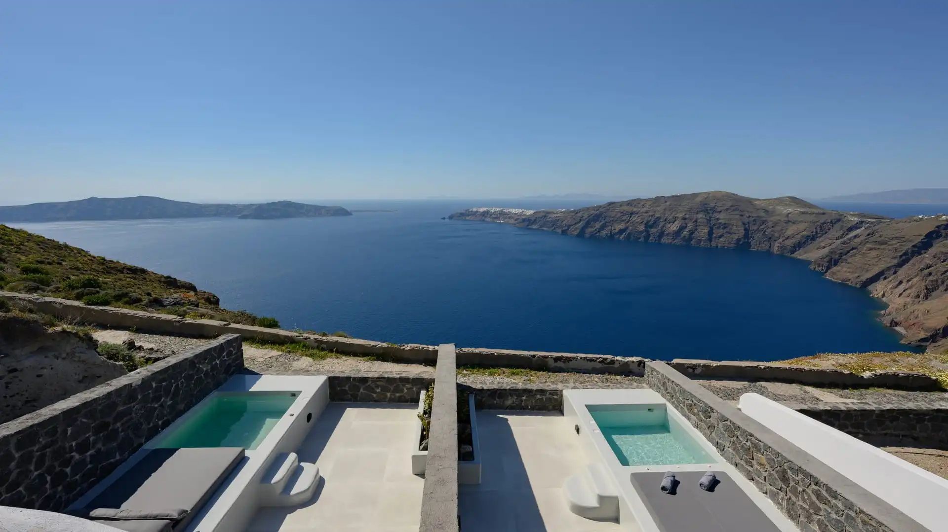 Terrasse mit zwei privaten Tauchbecken und weitem Blick auf das blaue Meer sowie die Steilküste.