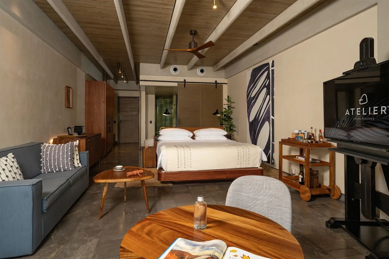 Modernes Hotelzimmer mit Doppelbett, Holzdeckenbalken, Sitzbereich und Holzmöbeln.