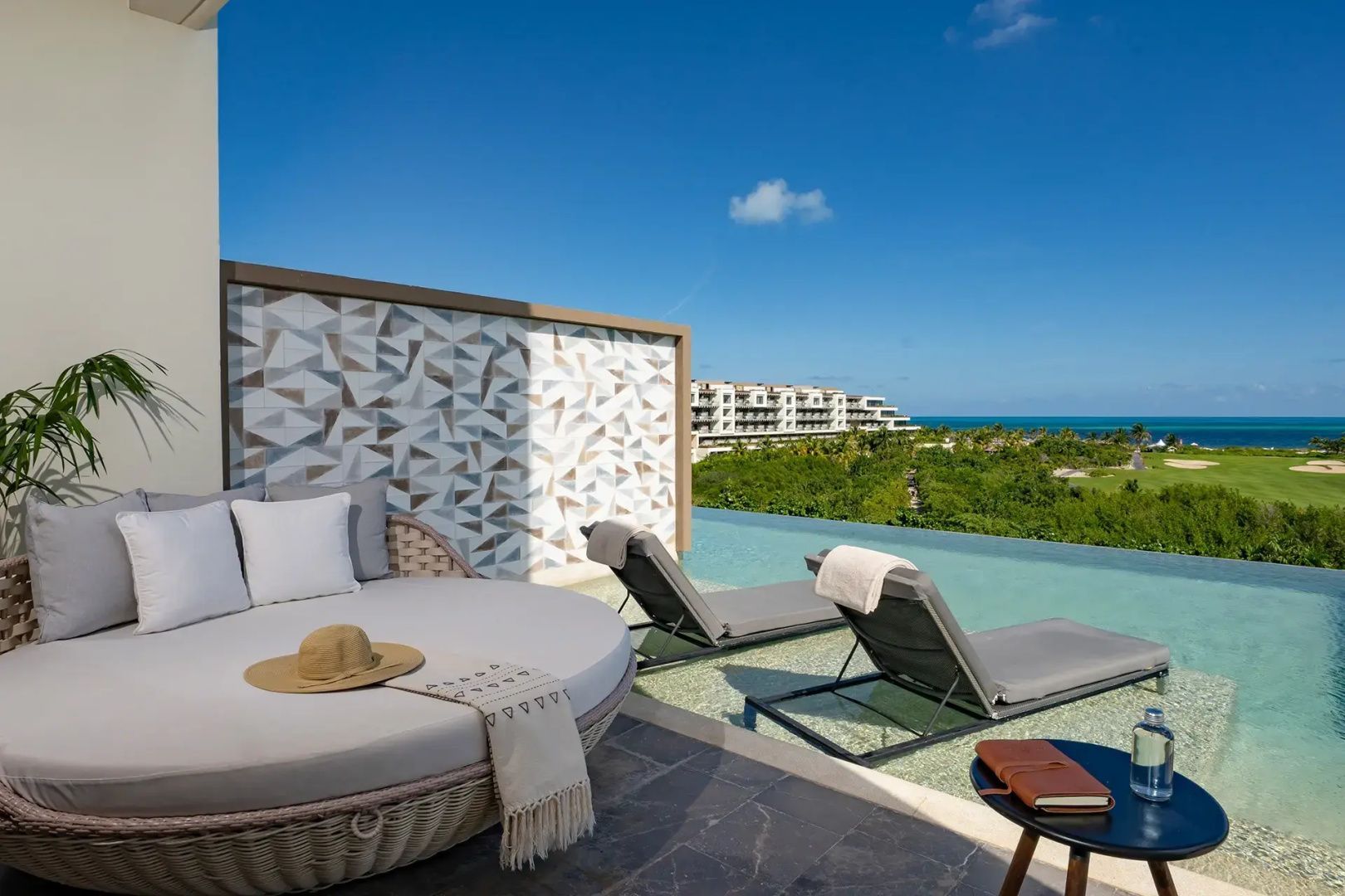 Sonnenterrasse mit Liegestühlen, einem Tagesbett und einem Pool mit Blick auf das Meer.